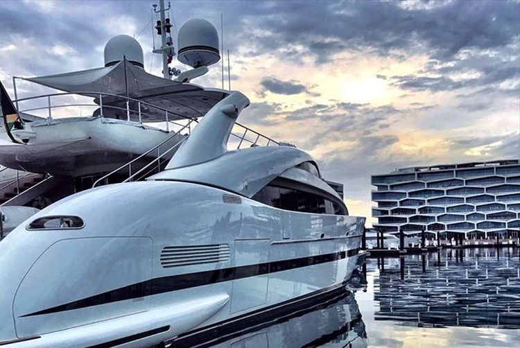 a superyacht in a marina in the evening as the sun sets