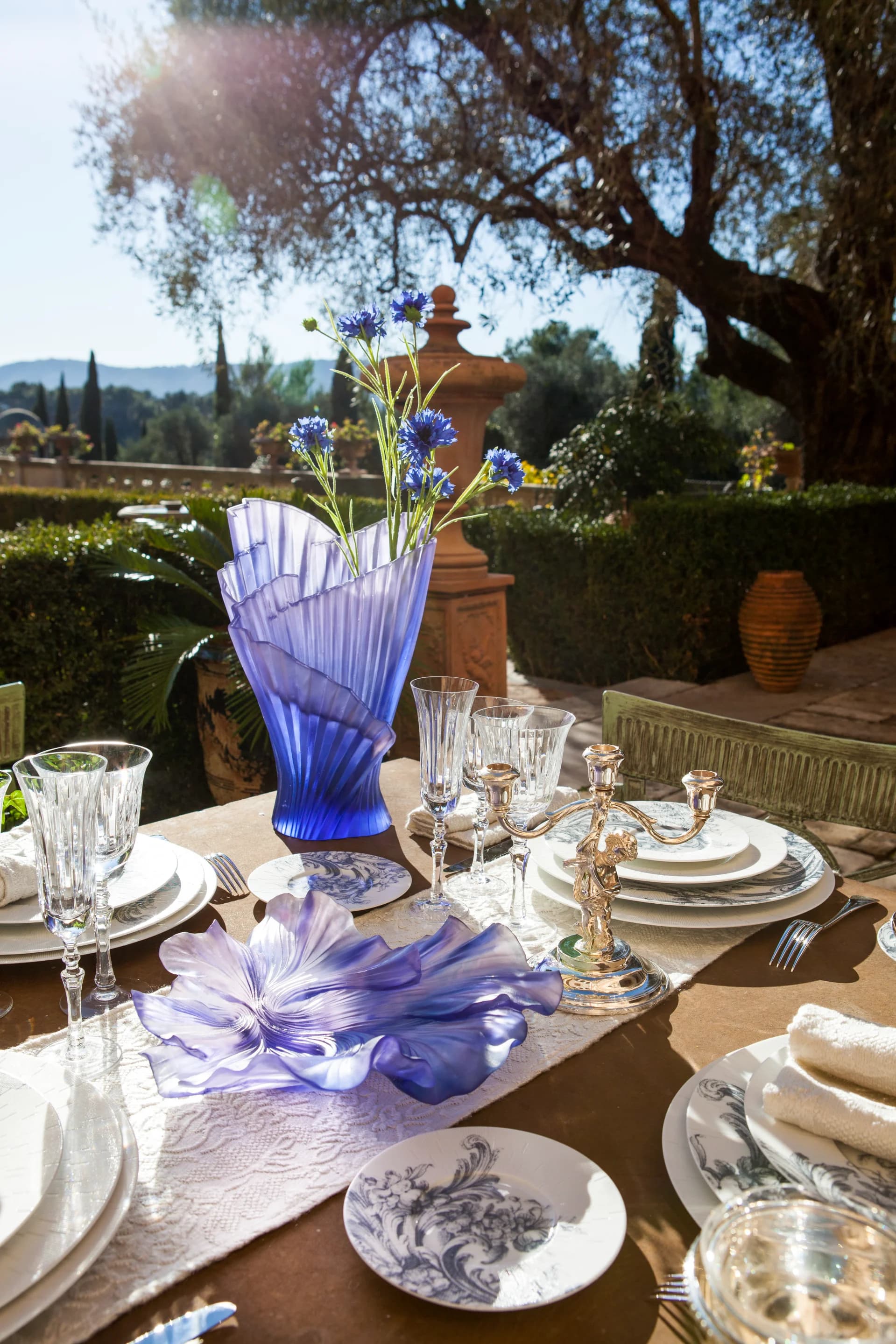 Daum Cruise Vase in blue, used as a beautiful centrepiece for outdoor dining in a stunning garden