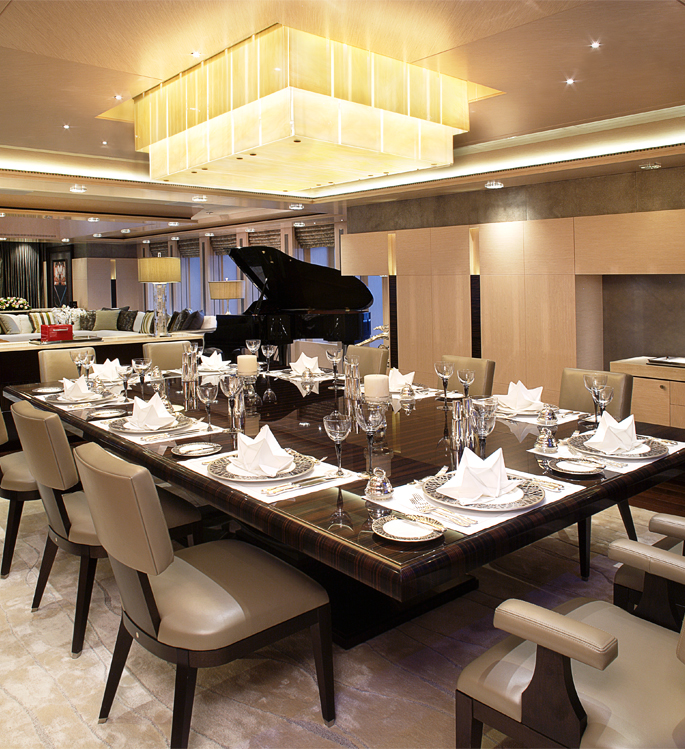 a vast dining room with a large table, luxury tableware and a grand piano