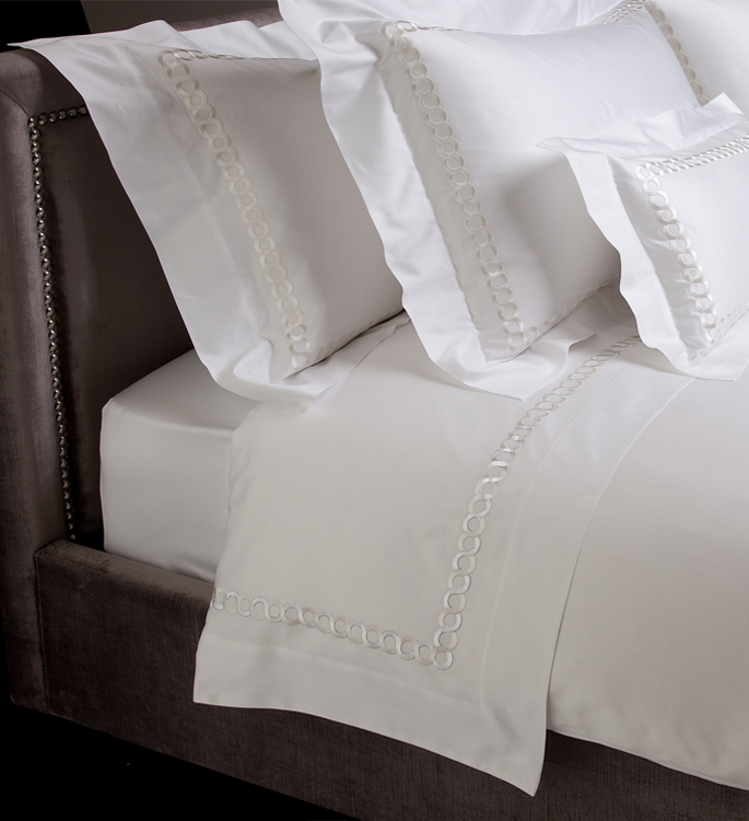 white bed linen with silver embroidery and an oxford border