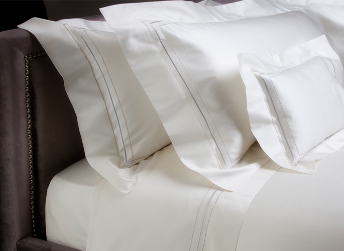 white bed linen with two embroidered lines and three pillows