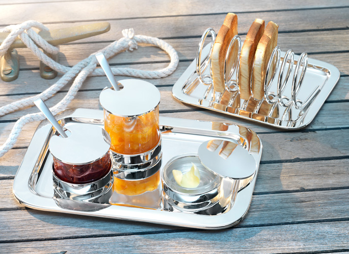 a sterling silver toast rack with a silver tray containing jams and spoons