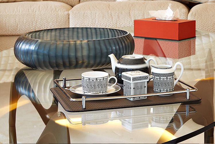 a table with a black and white hermes tea set with a red tissue box