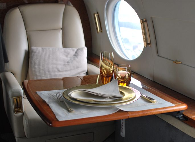 a private aircraft dining table by the window with luxury tableware and amber crystal