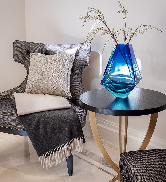 a chair with a luxury cashmere throw and a crystal vase