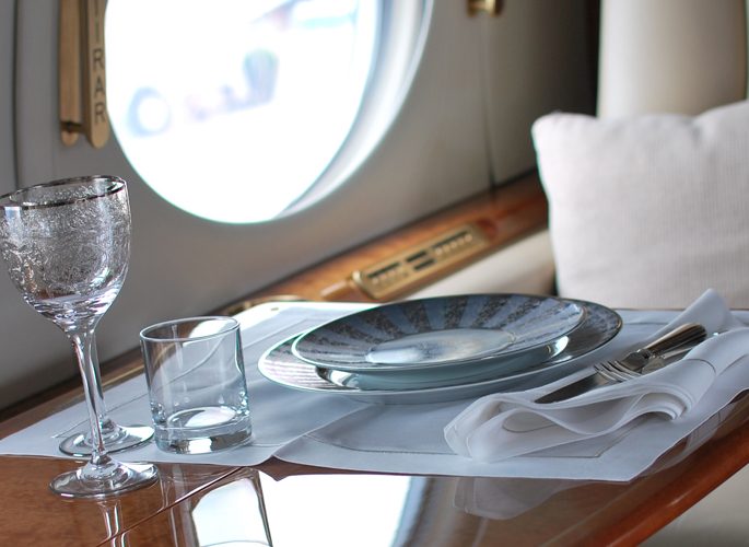 a private jet window with a dining setting of luxury tableware