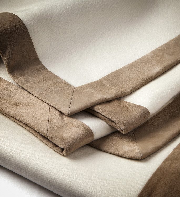 a cream cashmere throw with brown suede borders