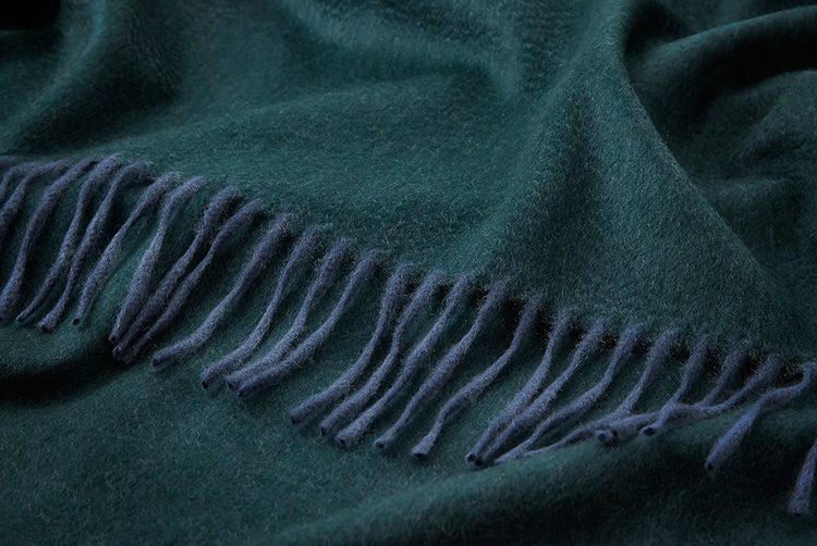 a dark green cashmere throw with darker blue tassles