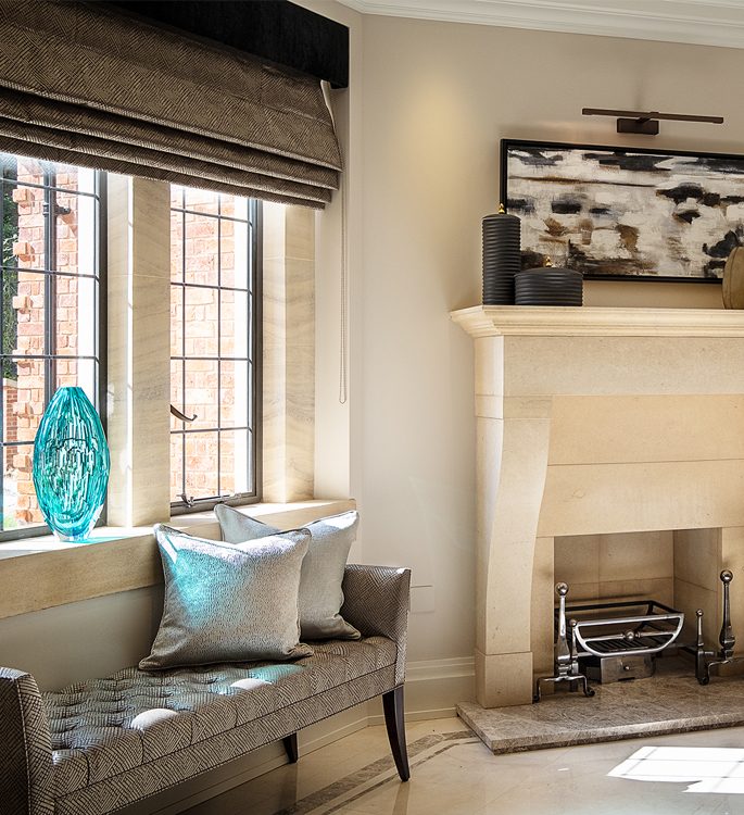 a fireplace with a long chair and lots of silver cushions