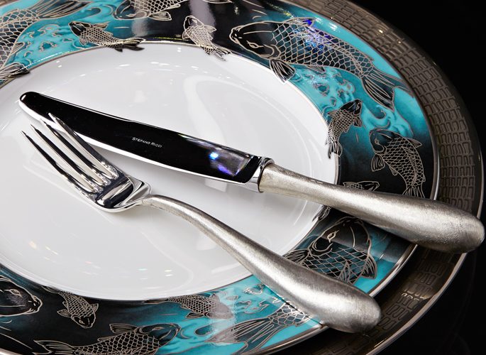 blue and silver koi carp fish patterned porcelain plate with table linen and cutlery