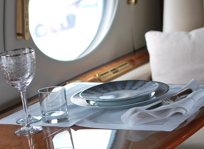a private jet window with a dining setting of luxury tableware