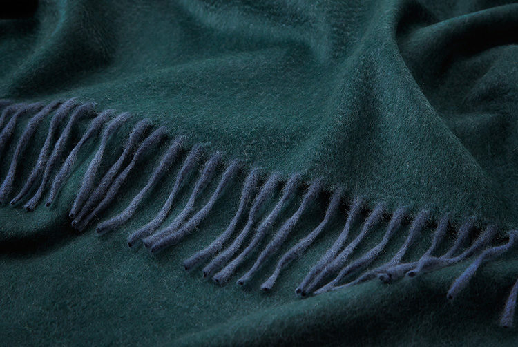 a dark green cashmere throw with darker blue tassles