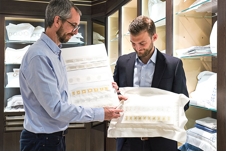 Design team within the Linens Showroom selecting embroidery patterns for a pillow