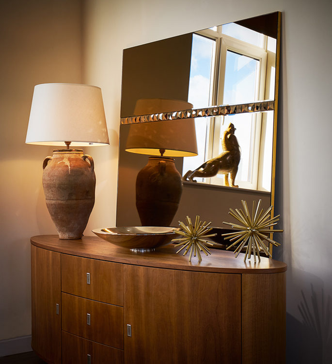 a swarovski crystal mirror behind a table with a lamp and decorative accessories