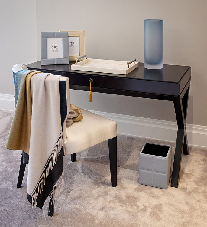 dressing table with photo frames, a trinket tray, vase and a cashmere throw hanging from the chair